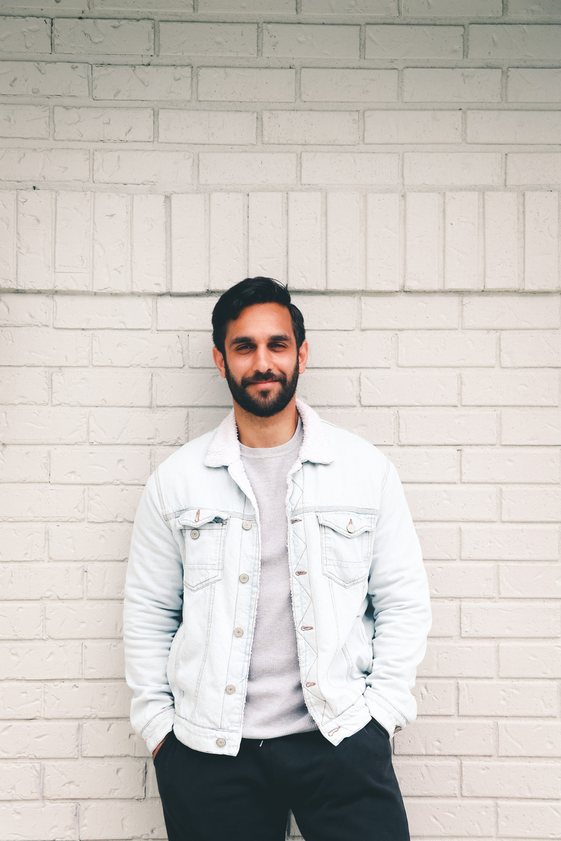 A Smiling Man Standing In Front of a Brick Wall